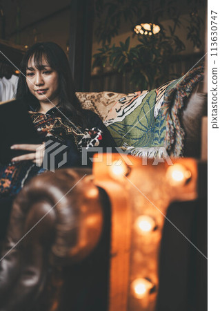 度假時，年輕女子在咖啡館靠窗的座位上喝咖啡時讀書 113630747