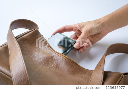 Woman put inside phone into brown leather handbag. Woman put inside phone into brown leather handbag. 113632977