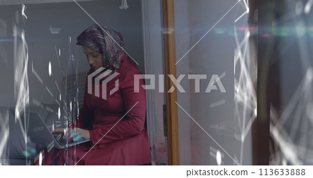 Image of digital interface with network of connections over woman in hijab using laptop computer 113633888
