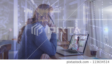 Spots of light against woman wearing phone headset having a image call on laptop Spots of light against woman wearing phone headset having a image call on laptop 113634514