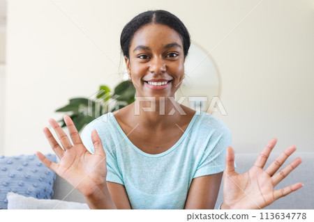 Young biracial woman smiles brightly at home on a video call Young biracial woman smiles brightly at home on a video call 113634778