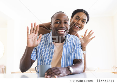 Joyful African American couple enjoys a playful moment at home on video call 113634844