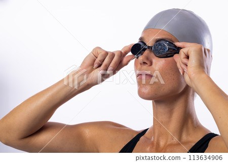 Young Caucasian female swimmer adjusts her swimming goggles 113634906