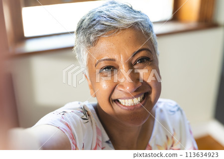 A mature biracial woman takes a selfie at home on a video call 113634923