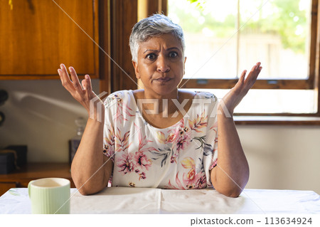 A mature biracial woman looks puzzled at home on a video call 113634924