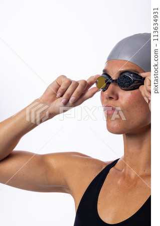 Young Caucasian female swimmer adjusts her swimming goggles, with copy space 113634931