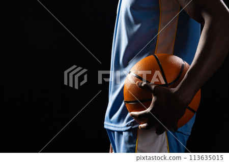 African American man holds a basketball on a black background, with copy space African American man holds a basketball on a black background, with copy space 113635015