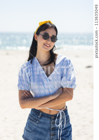 Young biracial woman stands confidently on a sunny beach 113635049