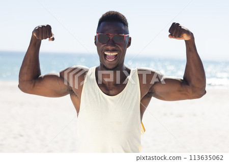 African American man flexes his muscles on the beach unaltered African American man flexes his muscles on the beach unaltered 113635062