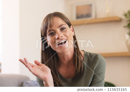 A middle-aged Caucasian woman gestures on a video call, cheerful in a home setting A middle-aged Caucasian woman gestures on a video call, cheerful in a home setting 113635165