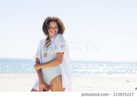 Young biracial woman enjoys a sunny beach day Young biracial woman enjoys a sunny beach day 113635227