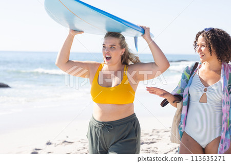 Young Caucasian woman and biracial woman enjoy a sunny beach day Young Caucasian woman and biracial woman enjoy a sunny beach day 113635271