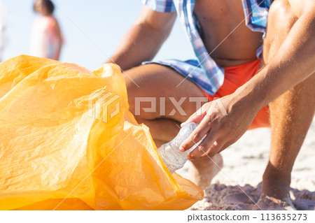 Person collects trash on a sunny beach 113635273