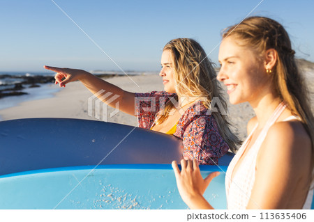 Two young Caucasian women enjoy a sunny beach day, with copy space 113635406