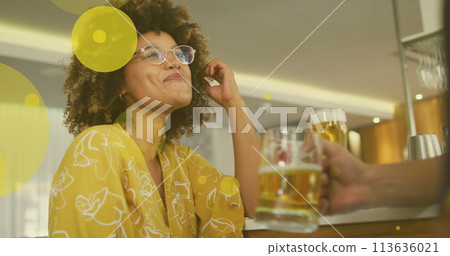Image of spots over happy biracial woman with caucasian friend drinking beer Image of spots over happy biracial woman with caucasian friend drinking beer 113636021