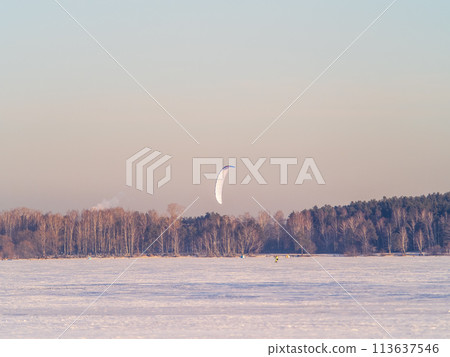 Kite surfer ride on snowboard. Snowkiting in the snow on frozen lake. 113637546