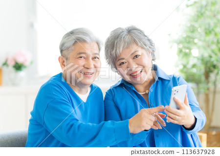 Senior couple looking at a smartphone in the living room 113637928