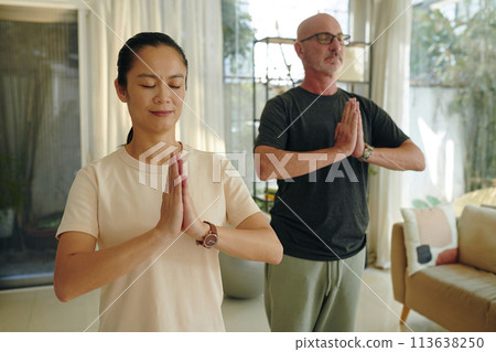 Smiling mature man and woman doing namaste gesture concentrating on breath 113638250