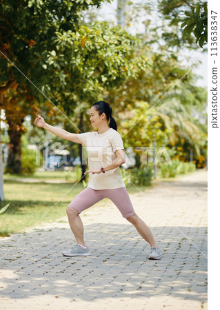 Fit mature woman exercising in park on sunny morning Fit mature woman exercising in park on sunny morning 113638347
