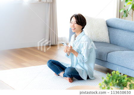Middle woman operating a smartphone in the room 113638630