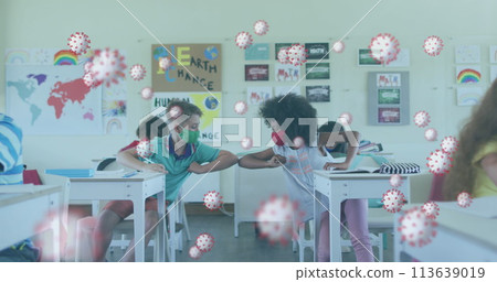 Covid-19 cells against two boys wearing face mask greeting each other by touching their elbows Covid-19 cells against two boys wearing face mask greeting each other by touching their elbows 113639019