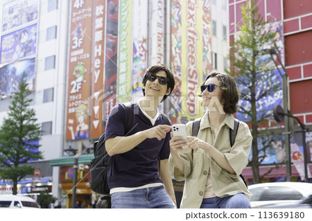 Inbound: A couple of foreign tourists strolling around Akihabara with smartphones in hand Inbound: A couple of foreign tourists strolling around Akihabara with smartphones in hand 113639180