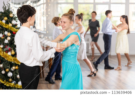 Smiling teenage girl enjoying slow dance with friend at Christmas party 113639406