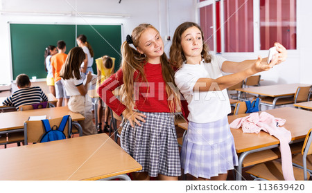 Two positive schoolgirls are photographed during a break in school class 113639420