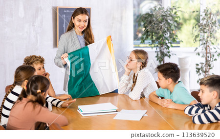 School teacher tells students about Ireland and holds Ireland flag in her hands. 113639520