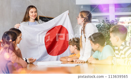 Female teacher shows scholchildren national flag of Japan 113639565