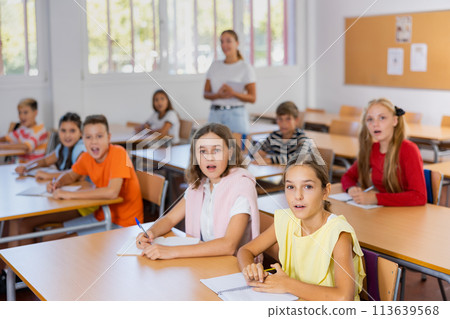 Surprised tween schoolchildren sitting at school desks at lesson 113639568
