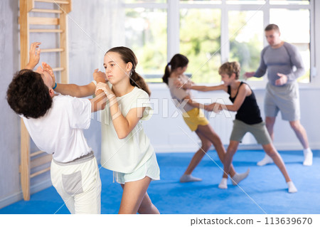 Boy and girl train to perform works out blow to jaw at opponent, while learning self-defense Boy and girl train to perform works out blow to jaw at opponent, while learning self-defense 113639670
