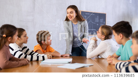Portrait of female teacher giving lesson to children in school class 113639685