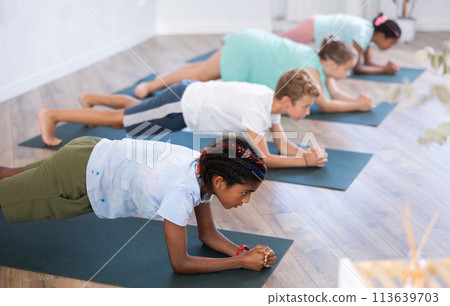 Training yoga kids on yoga mat in gym. 113639703
