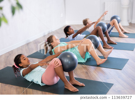 Group of multiethnic children doing pilates with soft ball Group of multiethnic children doing pilates with soft ball 113639727