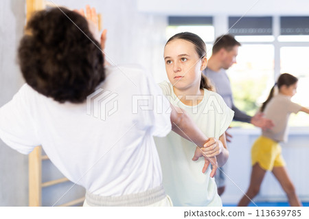 Boy and girl train to perform works out blow to jaw at opponent, while learning self-defense Boy and girl train to perform works out blow to jaw at opponent, while learning self-defense 113639785
