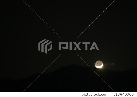 The fourth day of earthshine setting behind the edge of the mountains 113640306