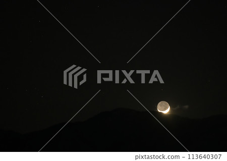 The fourth day of earthshine setting behind the edge of the mountains 113640307