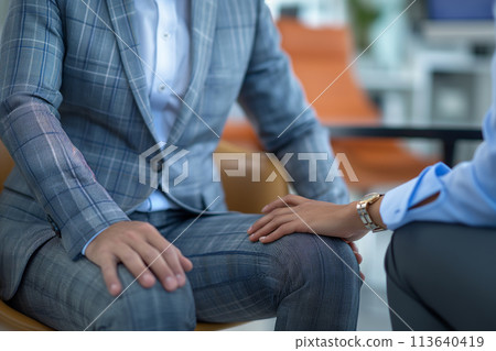 A woman touches the leg of a business man in a suit A woman touches the leg of a business man in a suit 113640419