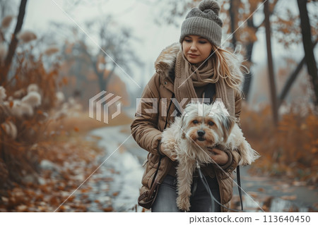 Stylish woman holding dog while walking on footpath 113640450
