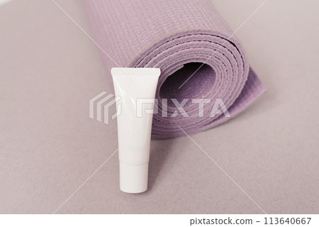 White tube of cream lies next to the yoga pink mats 113640667