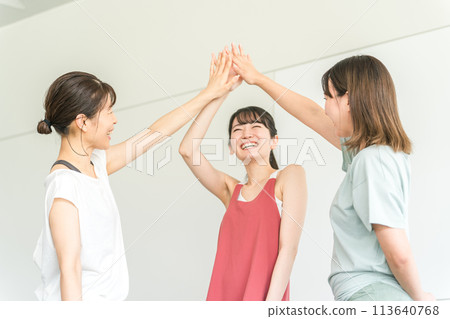 Women in sportswear high-fiving each other at the gym (teamwork, unity, hands) Women in sportswear high-fiving each other at the gym (teamwork, unity, hands) 113640768
