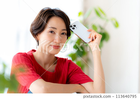 Middle woman operating a smartphone in the room Middle woman operating a smartphone in the room 113640795