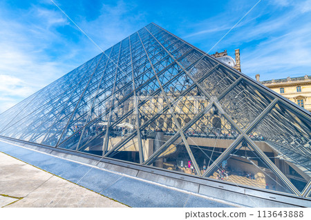 The iconic glass Pyramid at the Louvre museum basks under a clear blue sky. Paris, France 113643888
