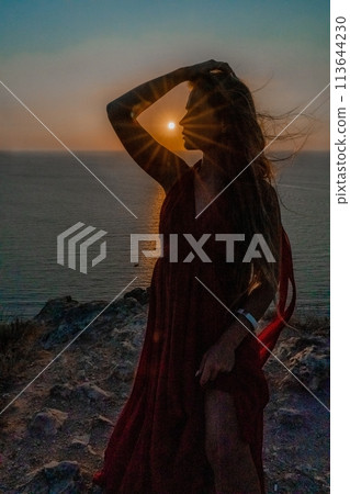 Woman sunset sea red dress, portrait happy beautiful sensual woman in a red long dress posing above the sea on sunset. 113644230
