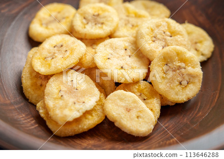 Dried organic bananas in wooden brown bowl top view. Crunchy dry fruit chips close up Dried organic bananas in wooden brown bowl top view. Crunchy dry fruit chips close up 113646288