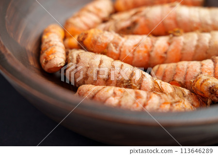 Organic turmeric roots in rustic wooden bowl. Many whole raw curcuma rhizomes. Indian natural seasoning ingredient 113646289