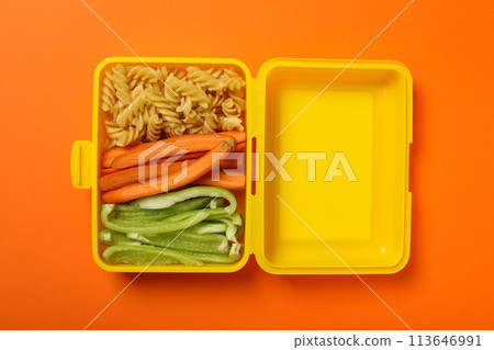 Yellow lunch box with food on an orange background Yellow lunch box with food on an orange background 113646991