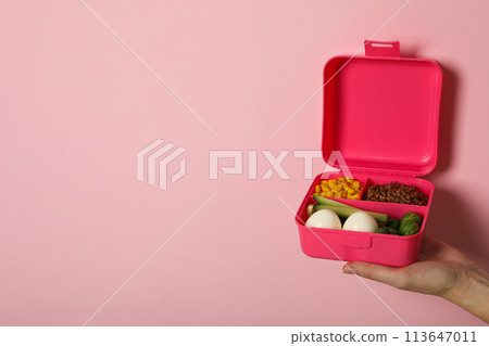 Pink lunch box in hands on pink 113647011