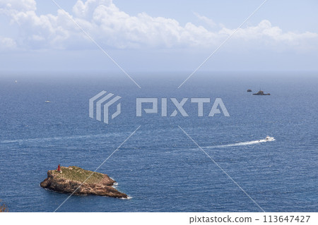 Speedboat leaves a trail heading to open sea from Eivissa, passing rocky islet with beacon Speedboat leaves a trail heading to open sea from Eivissa, passing rocky islet with beacon 113647427